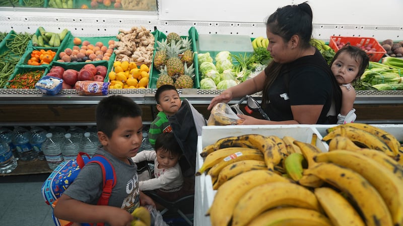 Una madre inmigrante originaria de Guatemala compra frutas para sus hijos con el saldo...