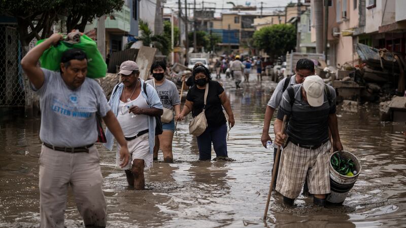 ARCHIVO - Personas caminan por una calle inundada en Poza Rica, en el estado de Veracruz,...