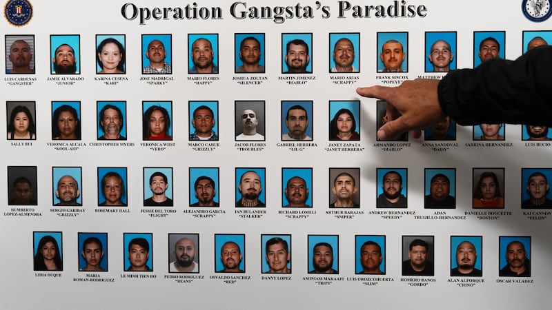 Un reportero apunta a una pizarra donde se muestra a individuos identificados por organismos...