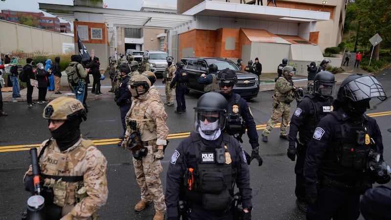 ARCHIVO – Agentes del orden público montan guardia en una calle para permitir que los...
