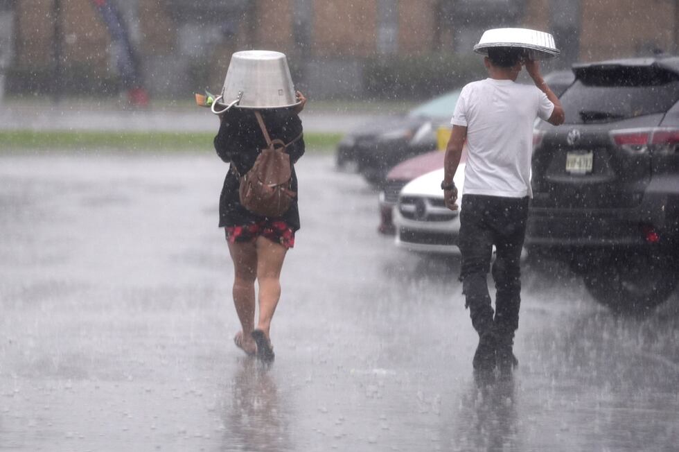 La gente se protege de un torrencial aguacero en Dallas el 24 de diciembre del 2024. (AP...